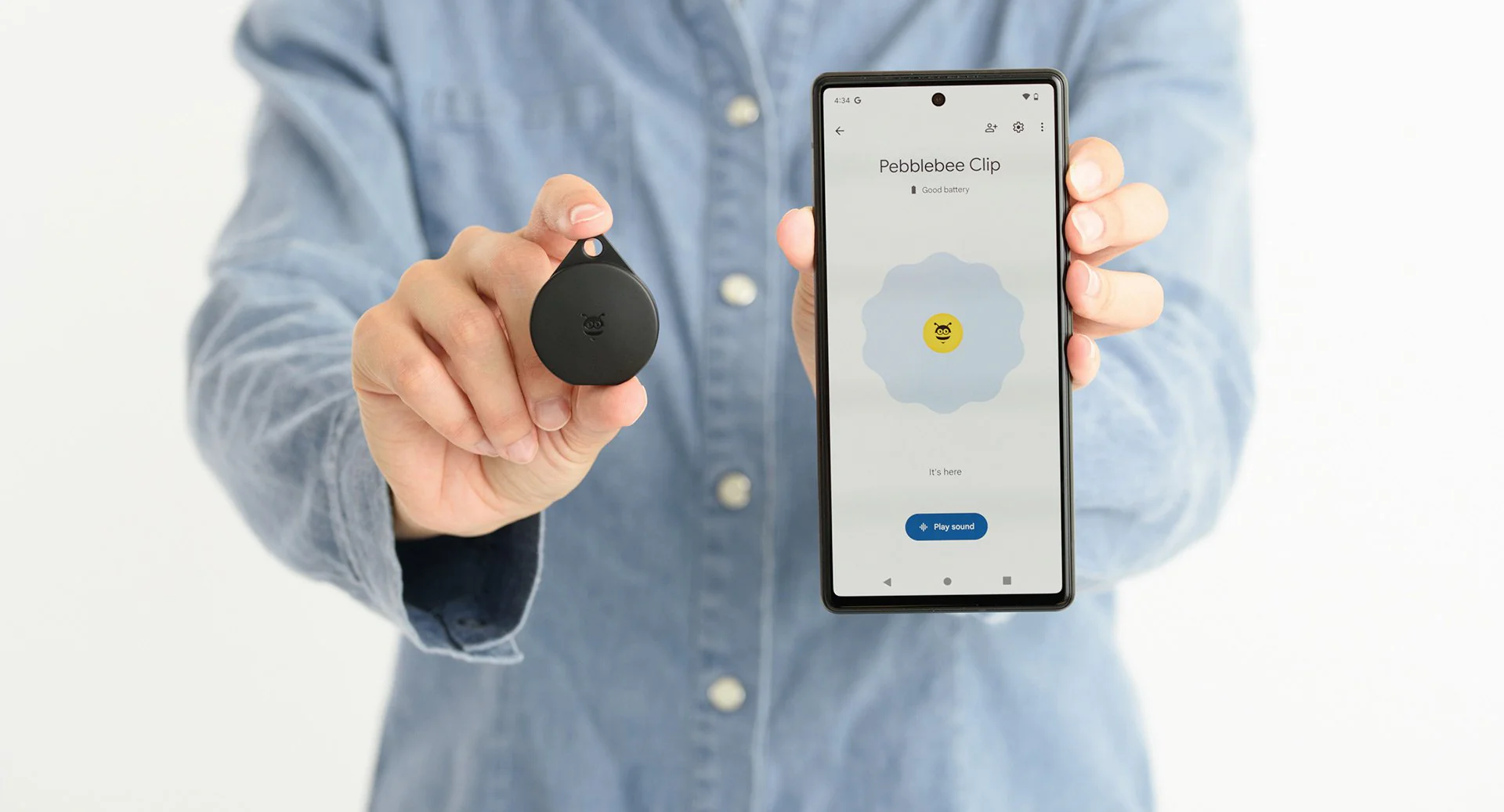 Person holding a Pebblebee Clip Bluetooth tracker alongside a phone displaying the Pebblebee app